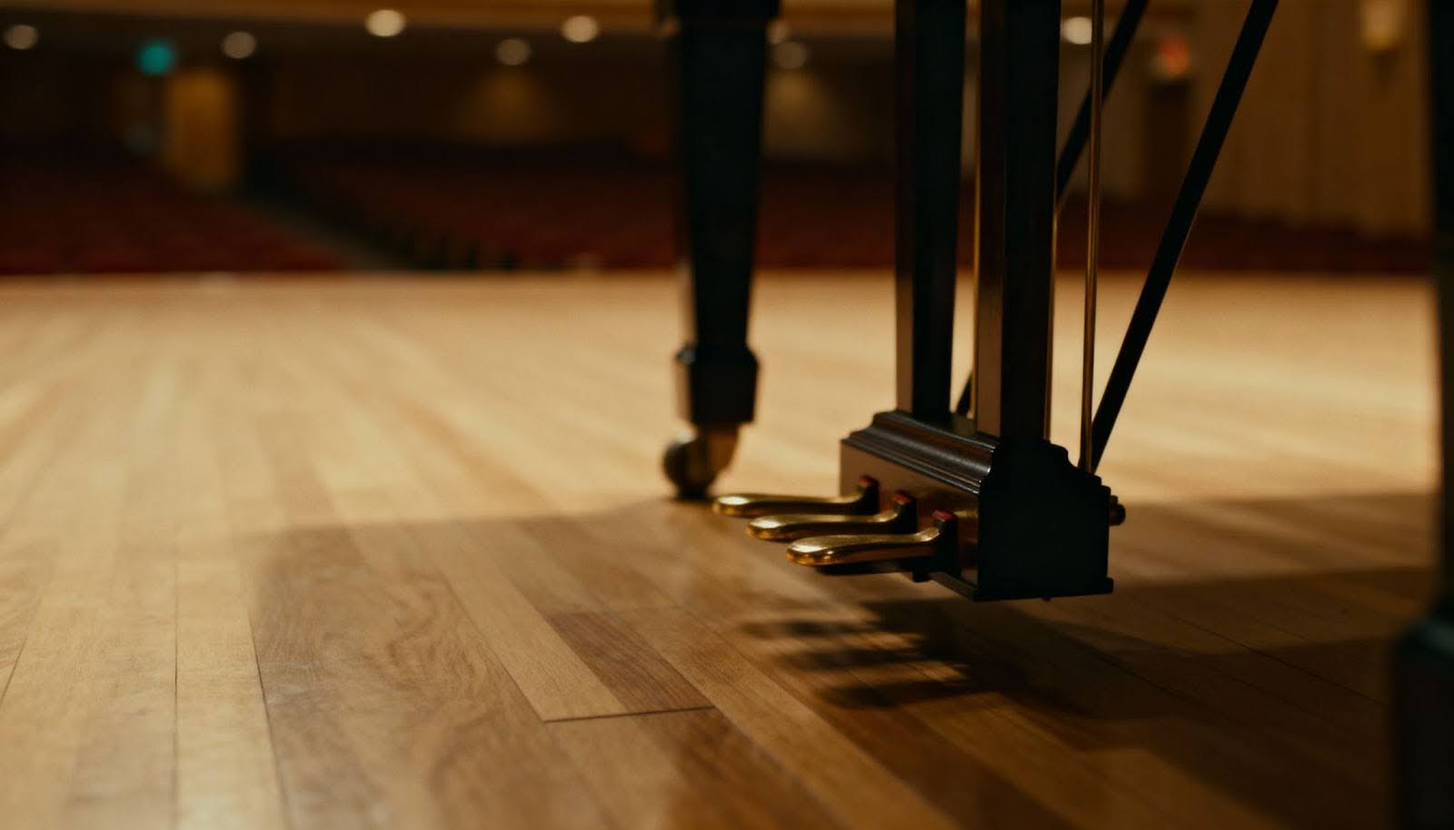 A close-up of grand piano pedals on a wooden floor